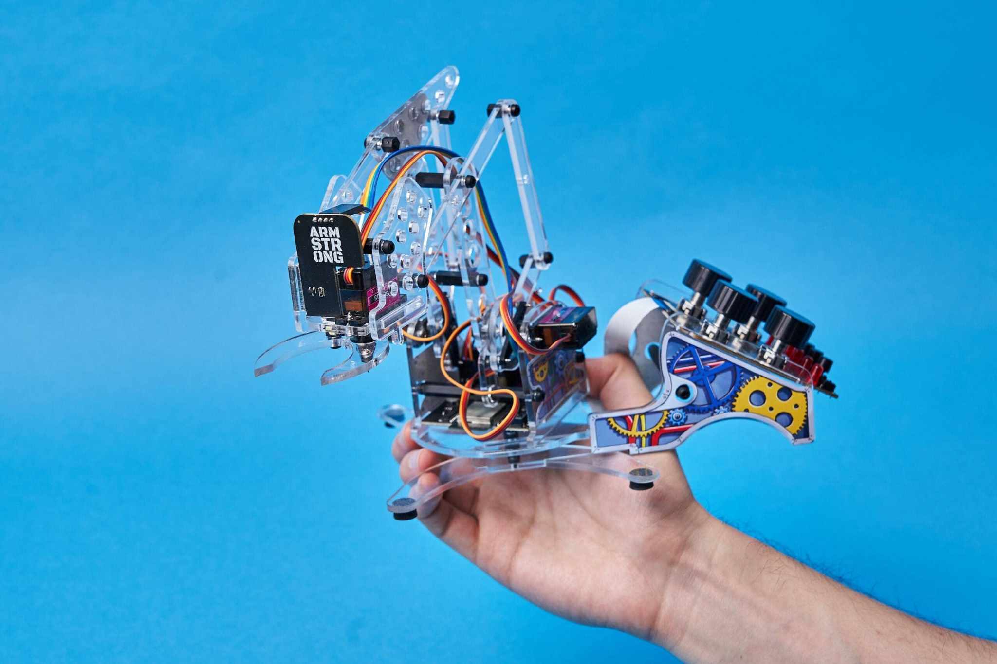 DIY color detecting programmable robotic arm kit being held on hand against blue background