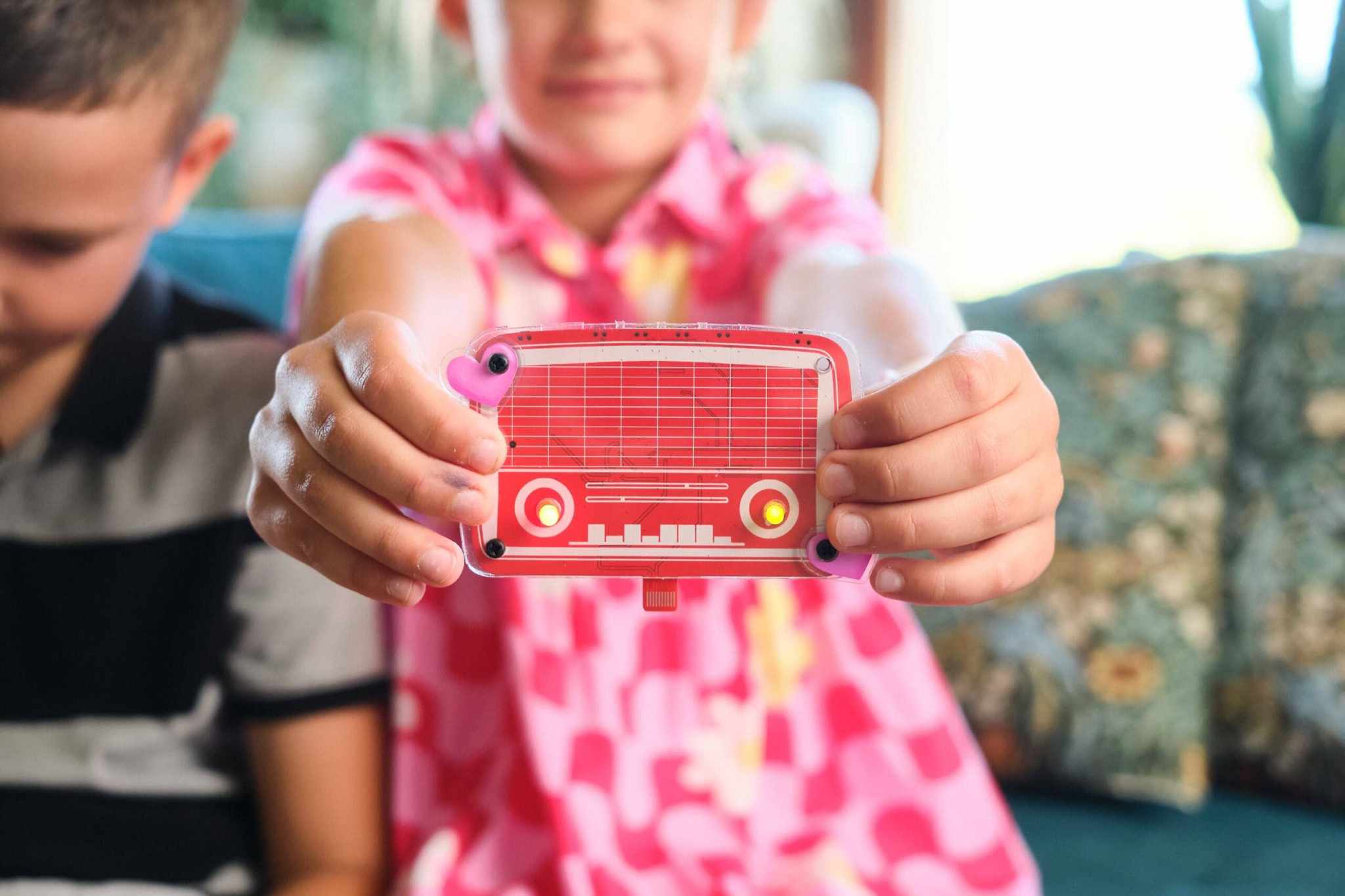 Child holding a Wacky Robot Hertz mini robot electronics kit with blinking lights.