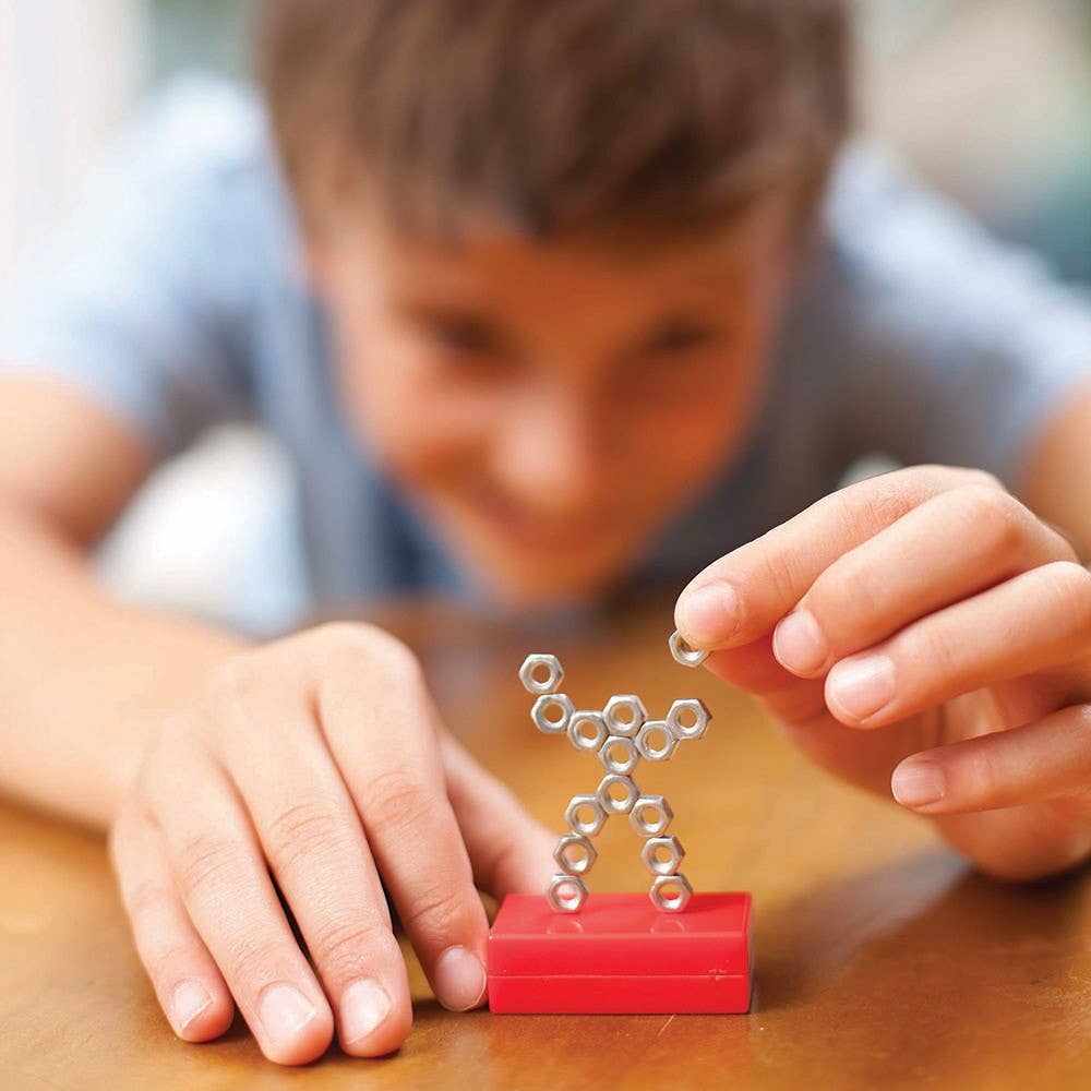 Child playing with magnetic nuts and bolts to create a figure using Magnet Science educational set