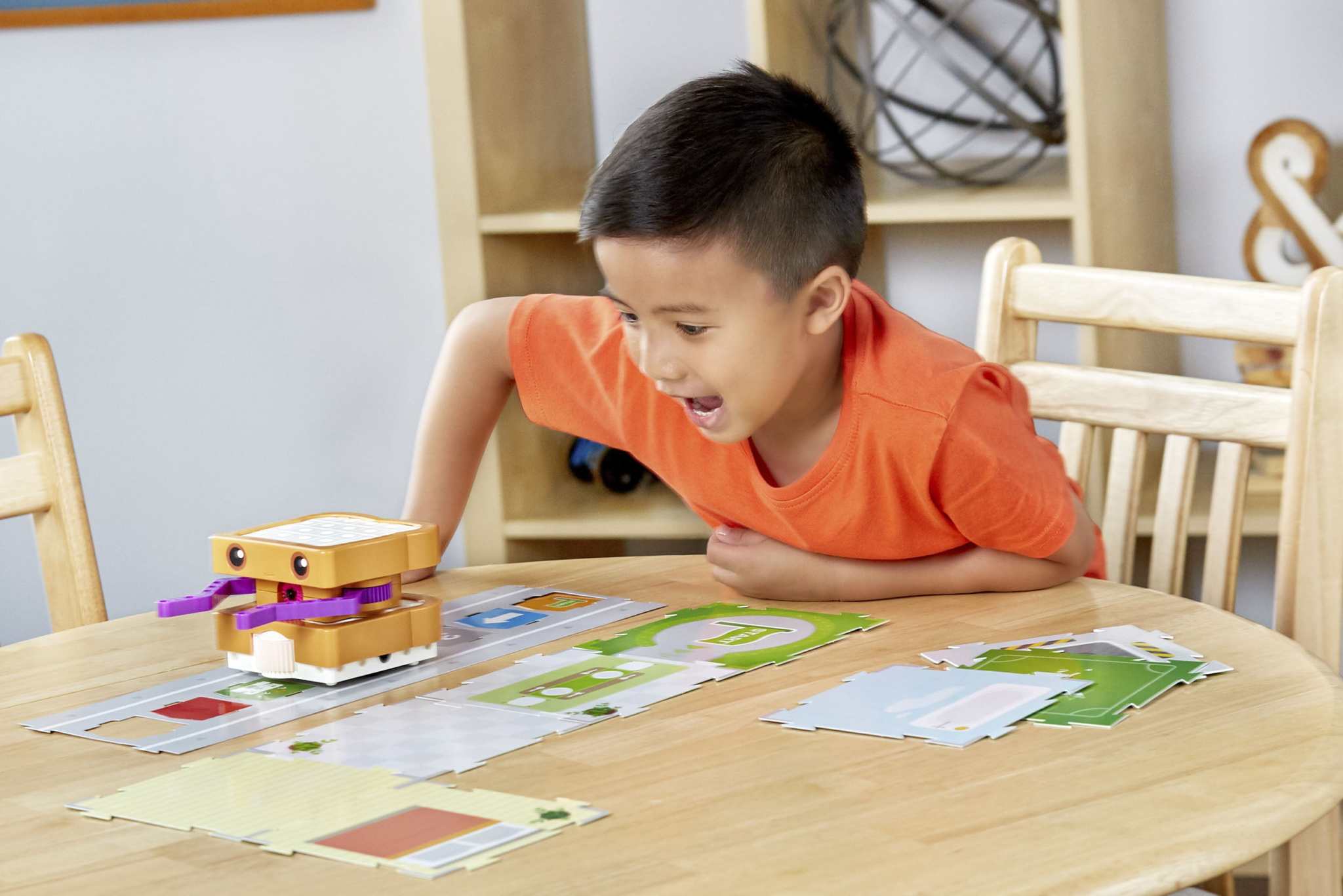 Child playing with Kids First Coding & Robotics robot and code cards on a wooden table