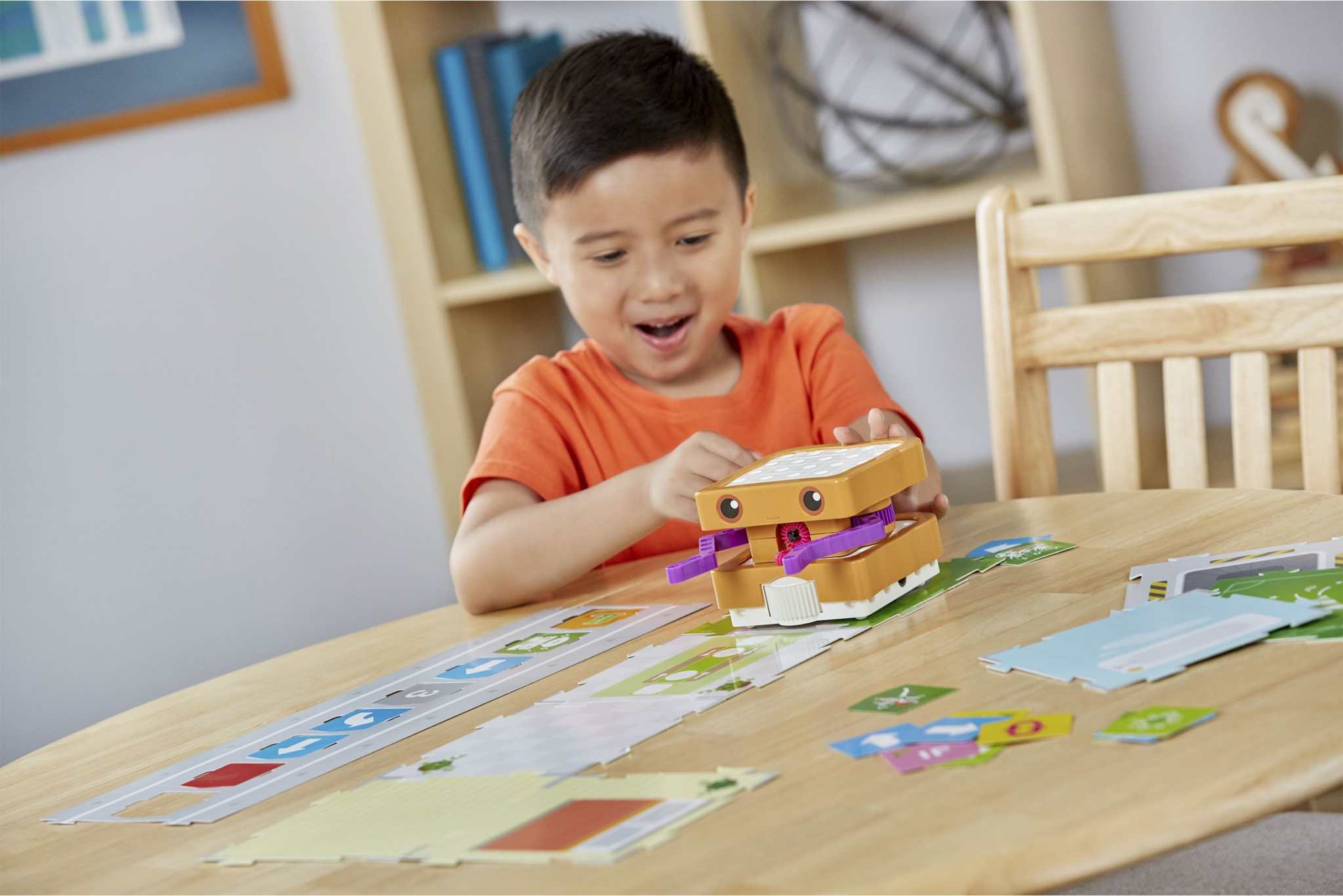 Child playing with Kids First coding and robotics robot on a table with code and map cards