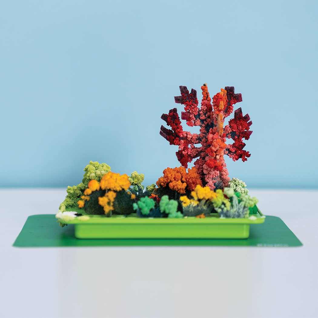 Crystal Chemistry Garden kit showing colorful crystal trees and bushes growing on a green base against a blue background