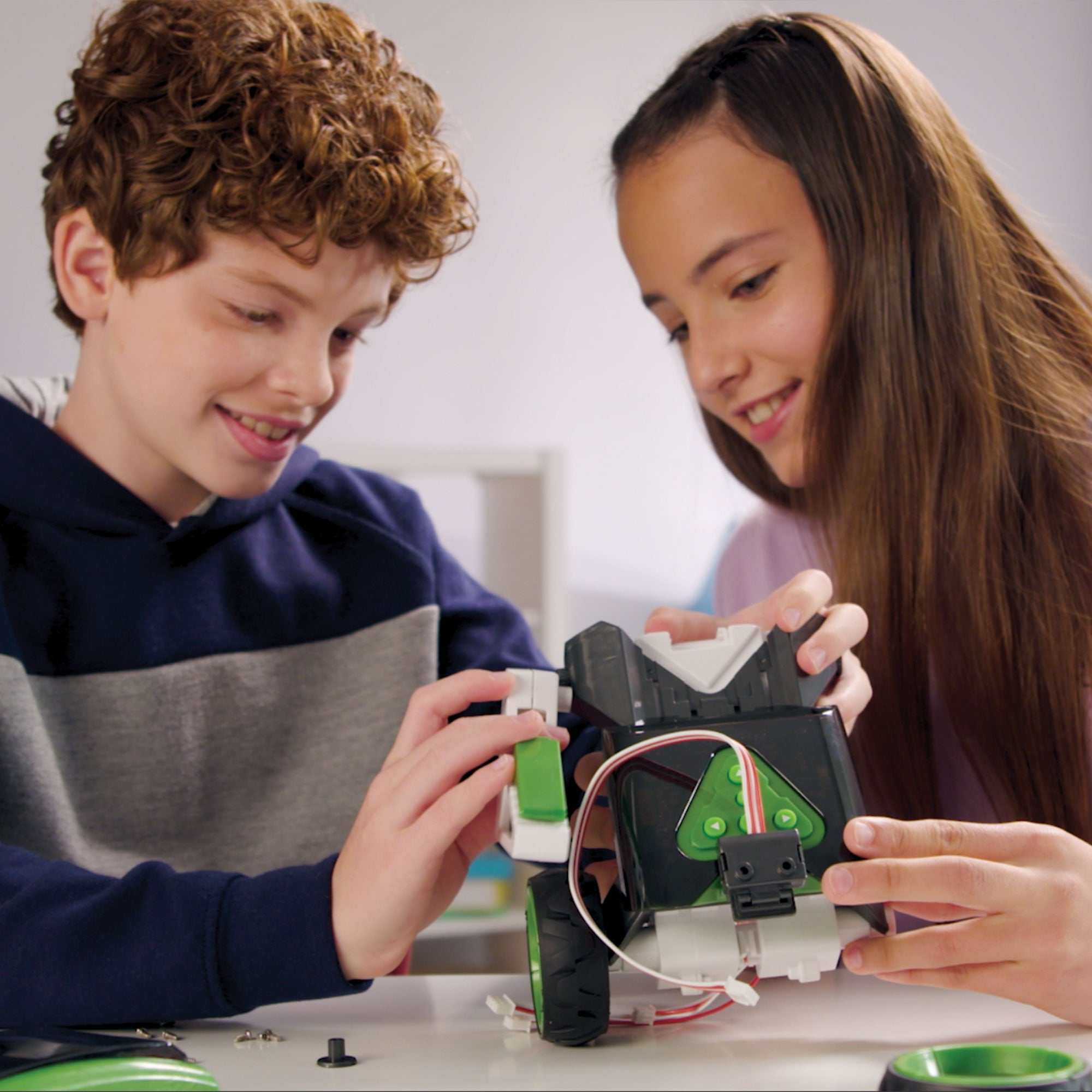 Two children assembling and programming the Robotics Smart Machines Sidekick robot kit at a table