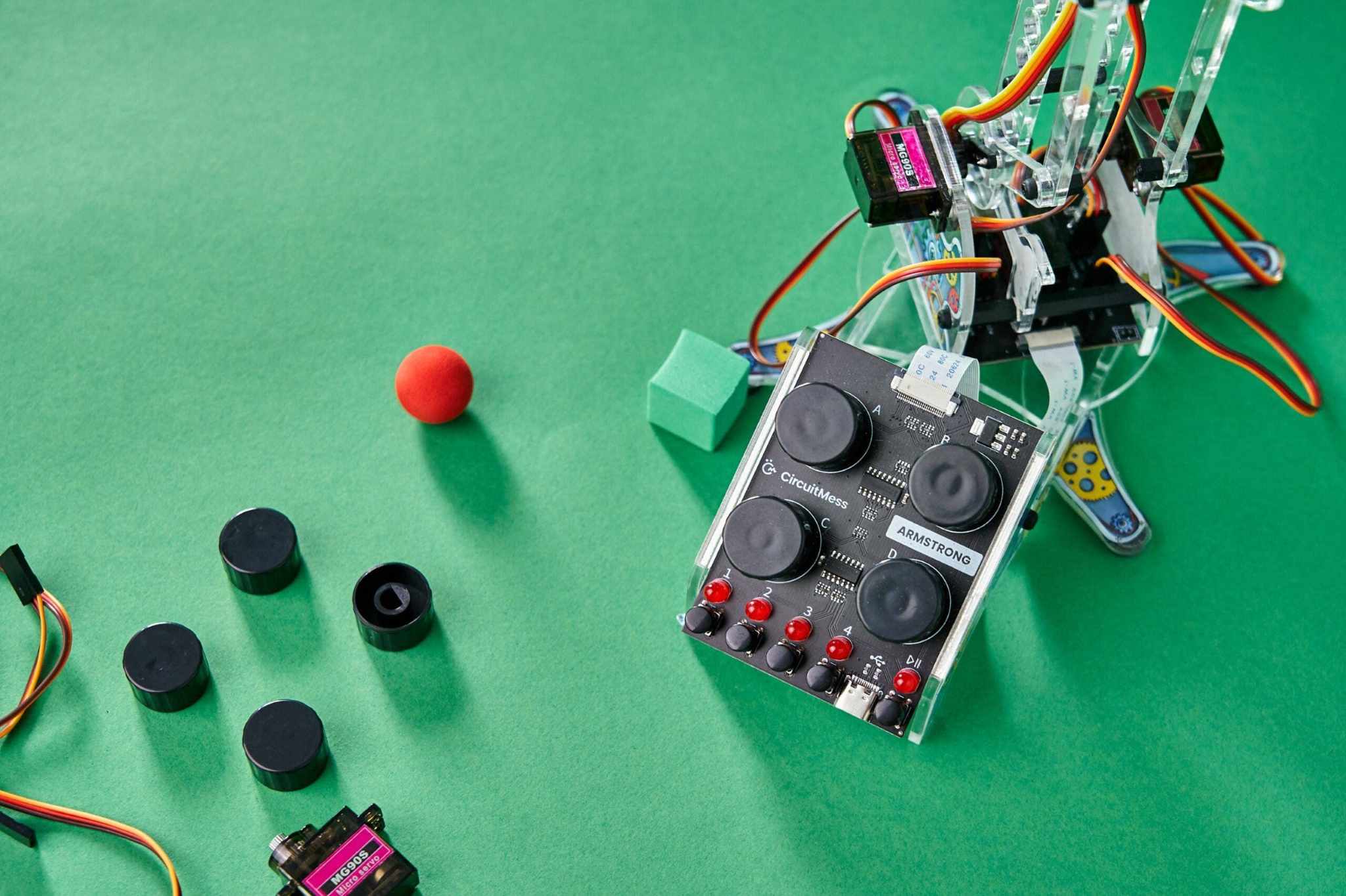 DIY color detecting robotic arm kit Armstrong with control panel and colored objects on green surface