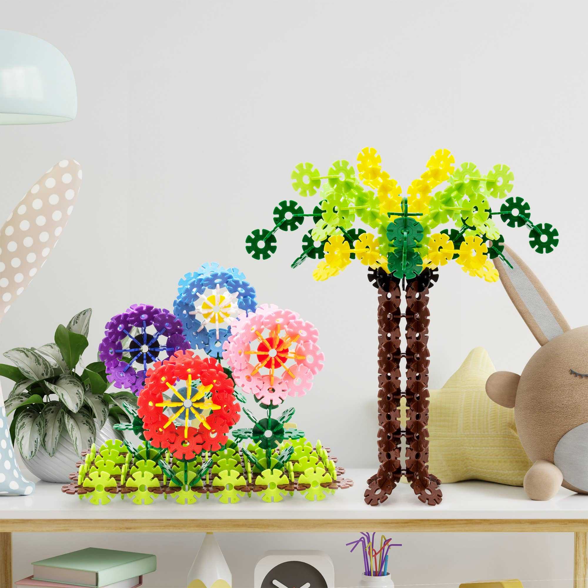 Colorful PicassoTiles Building Chips assembled into flowers and a tree on a wooden table for creative play