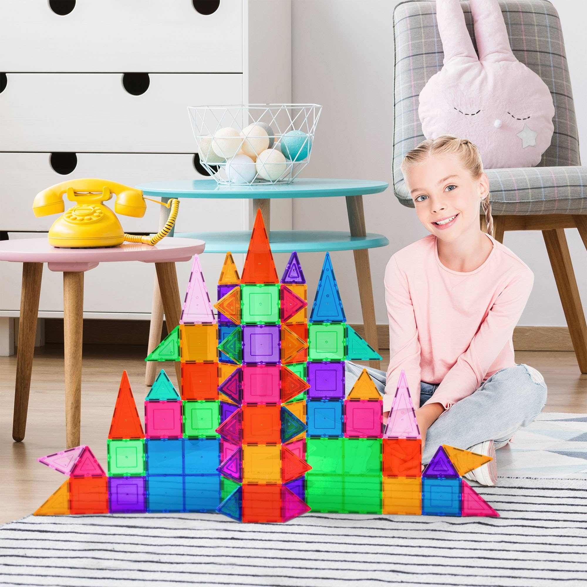 Child playing with colorful 101-piece magnetic tileset building structures in a bright room