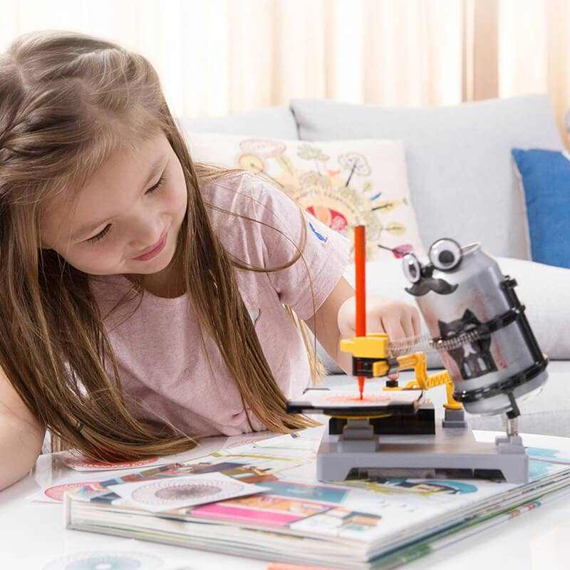 Child using the Arts Robot Spiral Factory STEAM kit to create spiral artwork with a recycled can robot on a table.