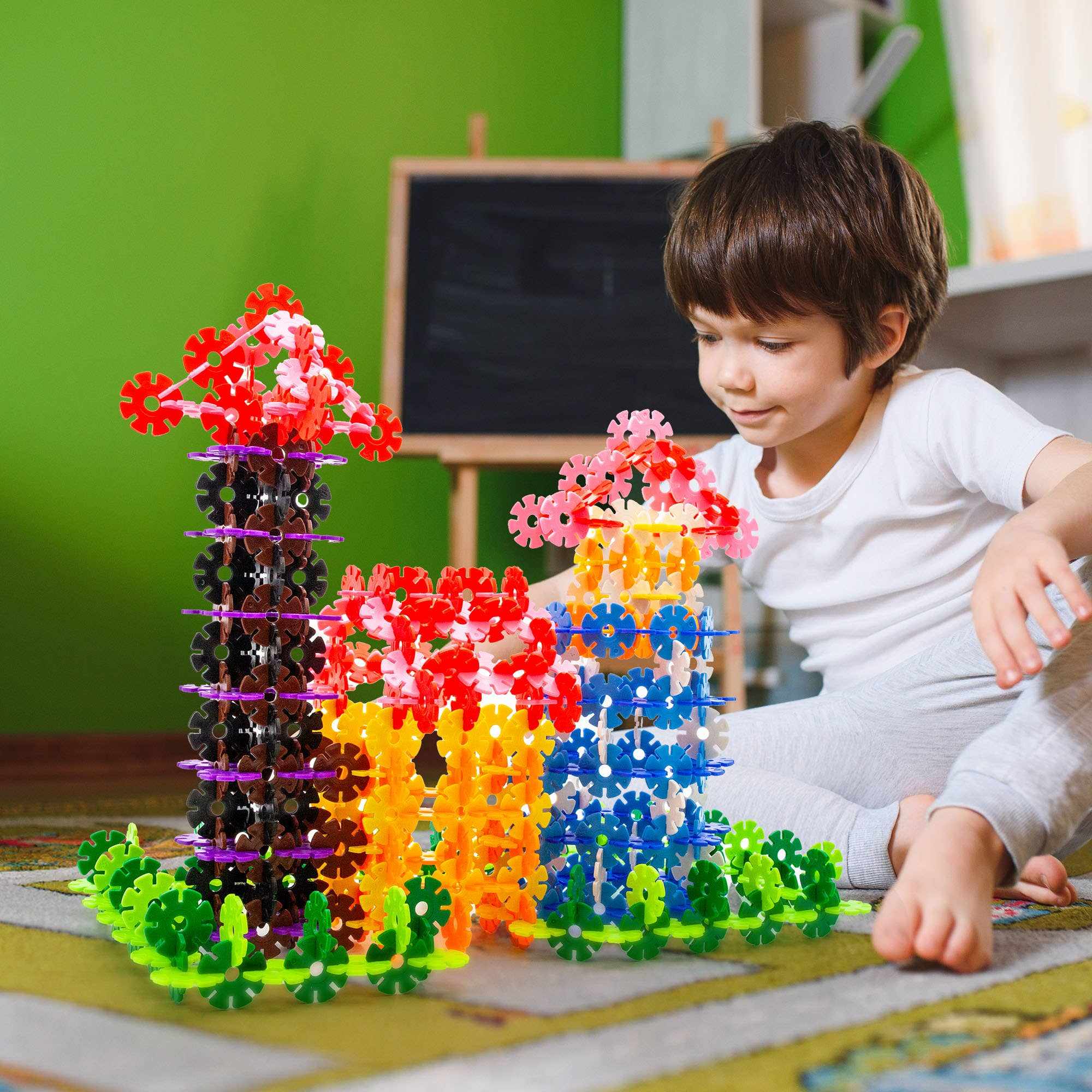 Child playing with colorful PicassoTiles 300pc Building Chips interlocking disc blocks on the floor