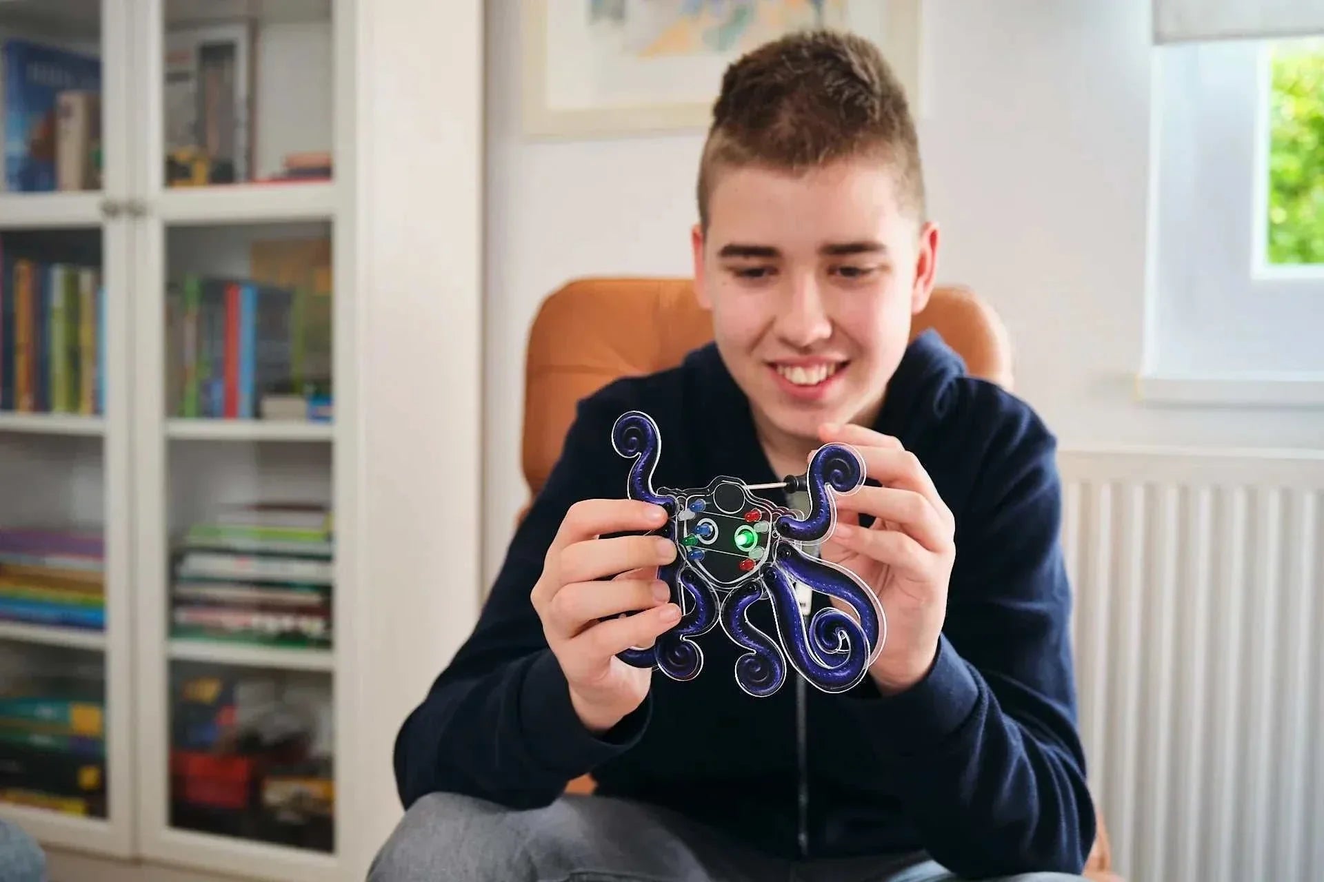 Boy holding and playing with Wacky Robot Artemis mini robot kit with blinking LED lights