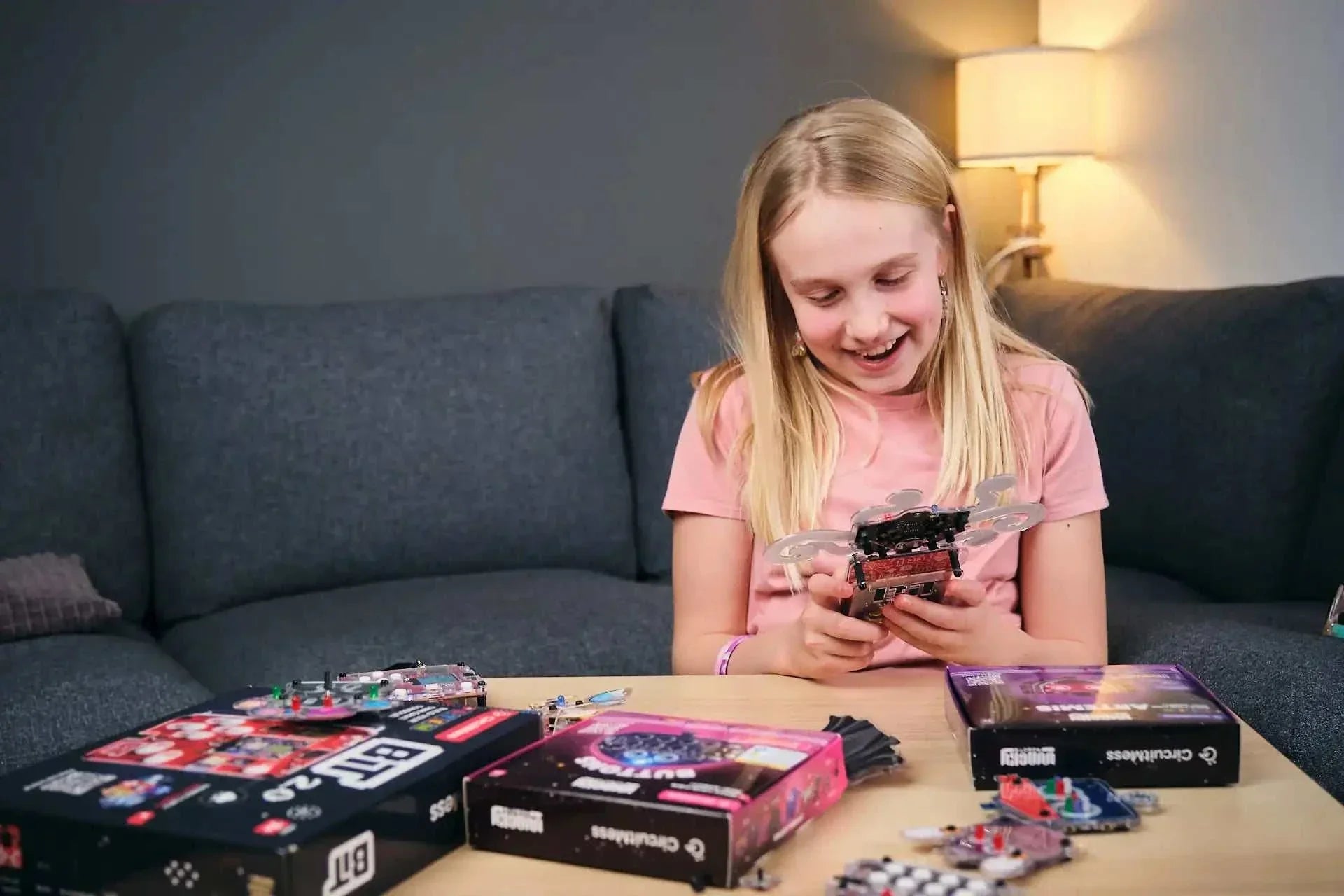 Girl assembling Wacky Robot Artemis mini robot kit with electronics and LED components on table.