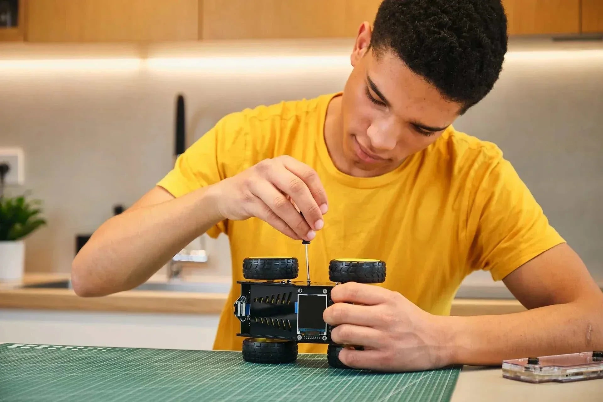 Teen boy assembling the Wheelson AI-powered self-driving robot car kit on a workbench