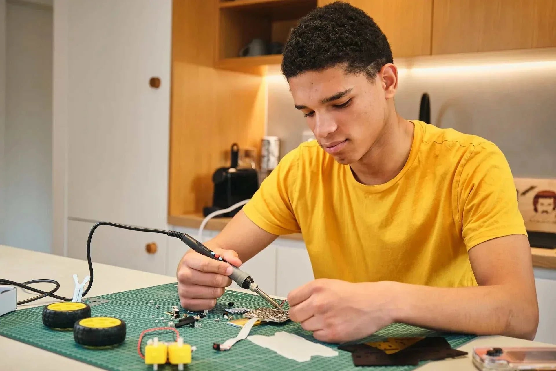 Teen soldering electronic components for Wheelson AI-powered self-driving robot car STEM kit