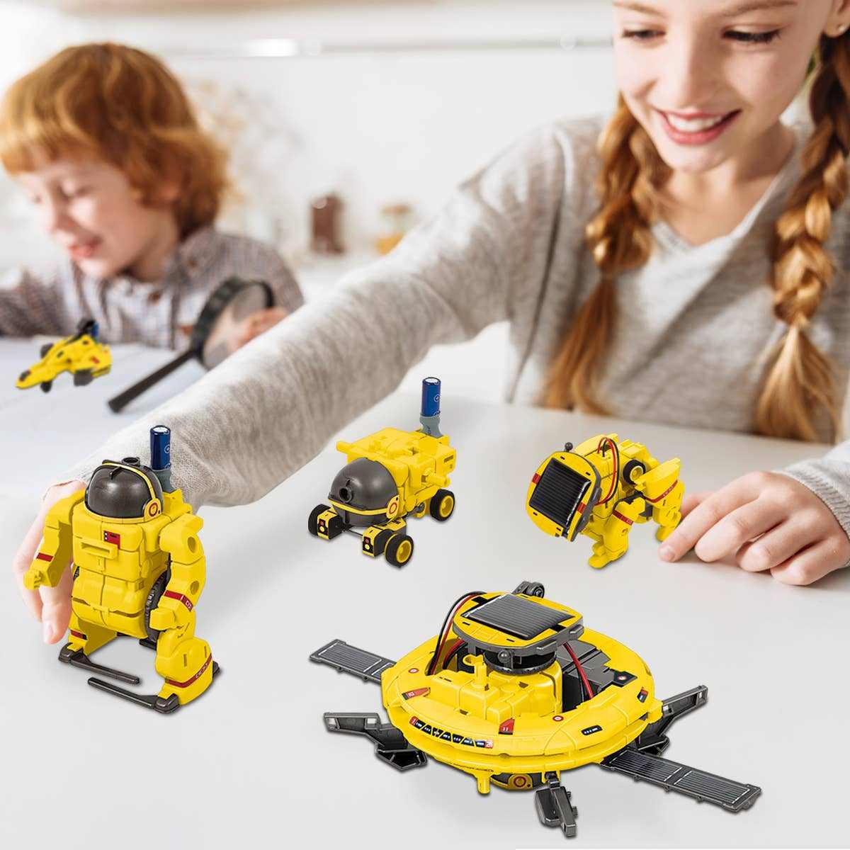 Children playing with yellow 6-in-1 STEM kids solar powered UFO robot science kit models on a white table.