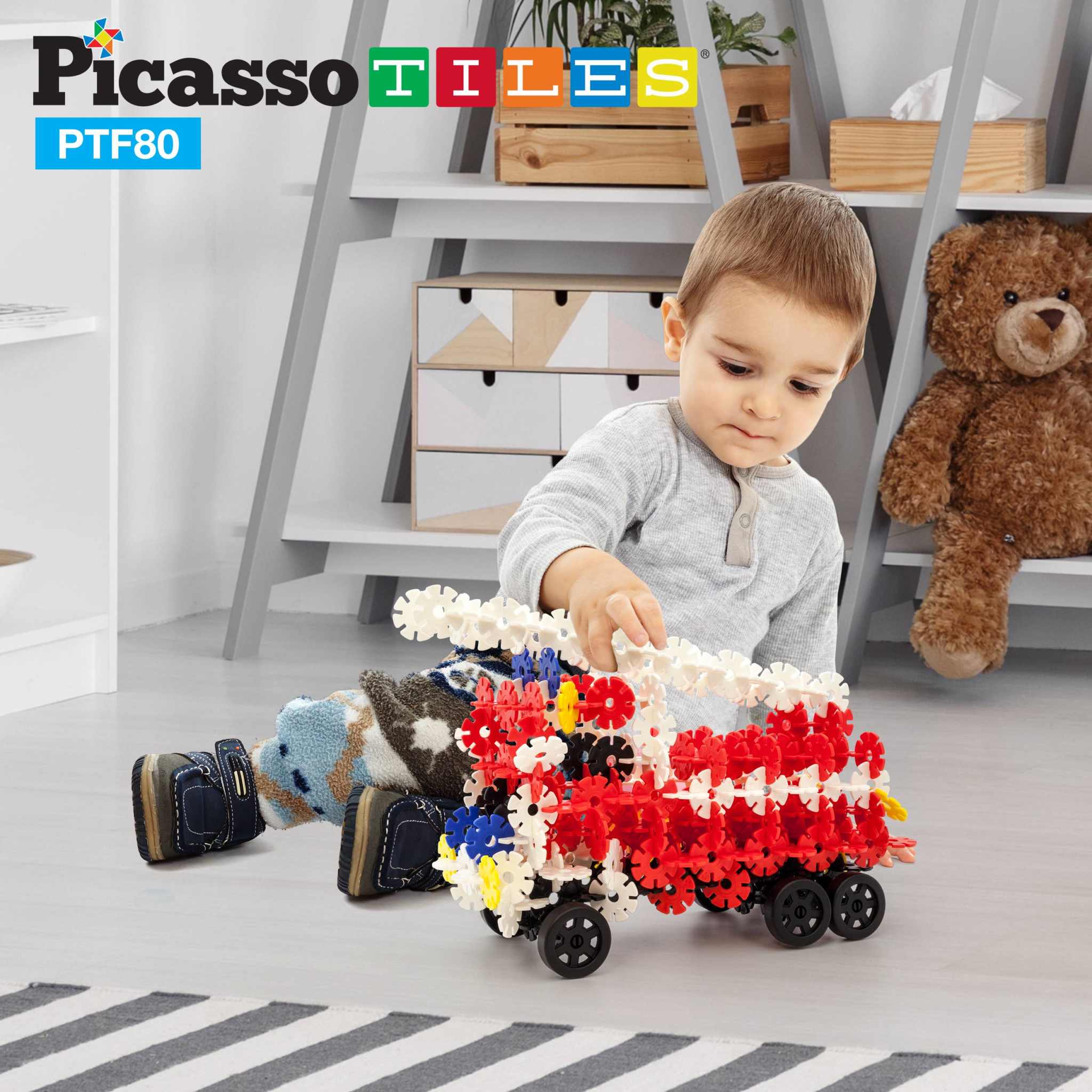 Child playing with PicassoTiles 800pc Building Chips set, constructing a colorful vehicle with wheels on the floor.