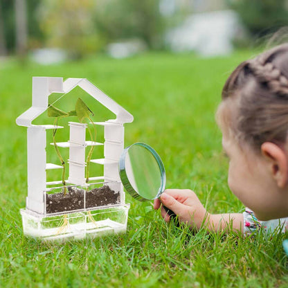 Child observing plant growth in PlaySTEAM Plant Maze Botany Kit with magnifying glass outdoors.