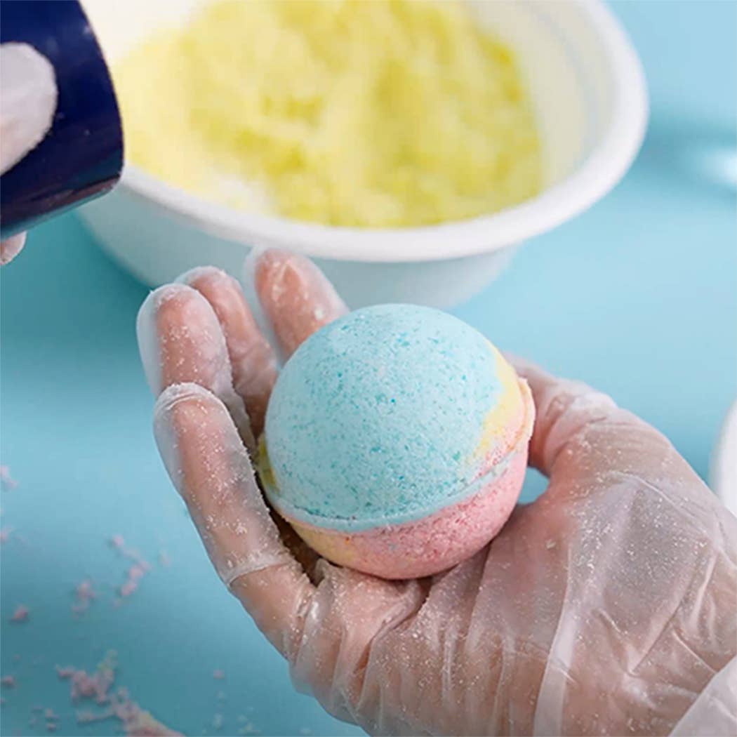Child's gloved hand holding a colorful layered planet-shaped bath bomb from the Planet Bath-Bombs Science Kit for kids.
