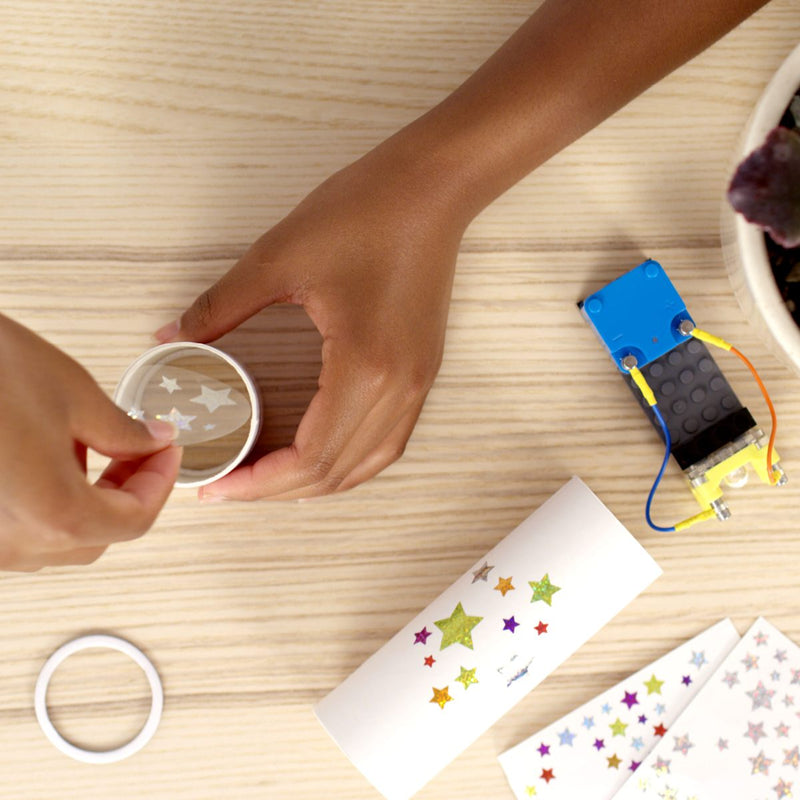 Child assembling circuit cubes STEM starter kit components with stickers on wooden table